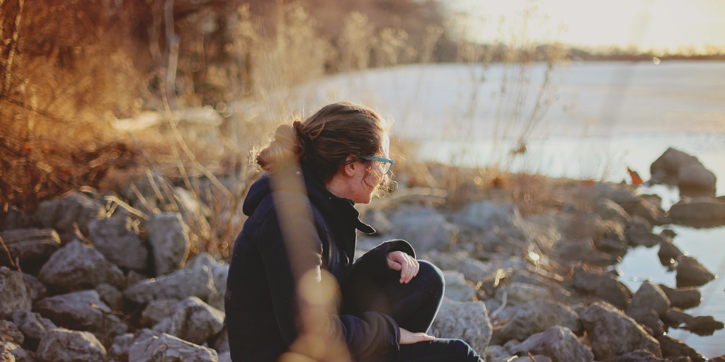 A lady sitting by a lake gazing at the sky