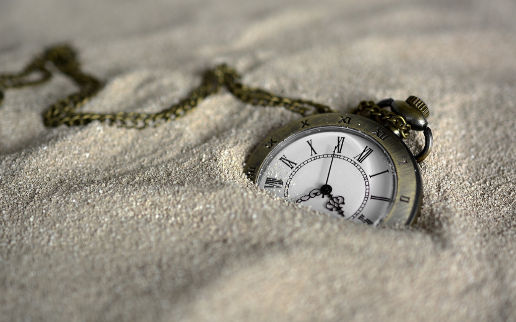 pocket watch buried in sand