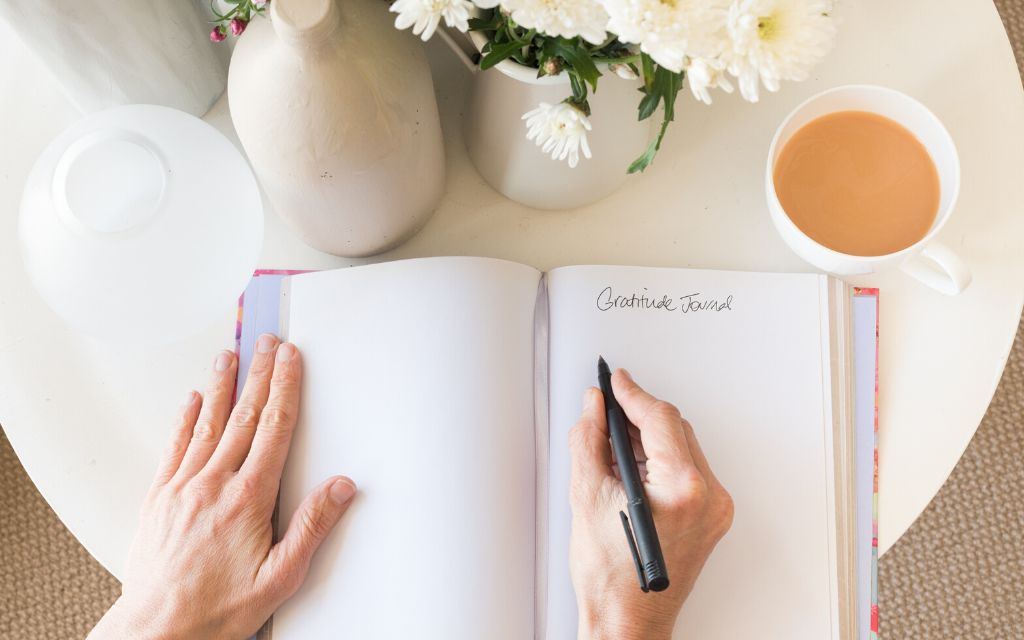 A woman writing on a gratitude Journal
