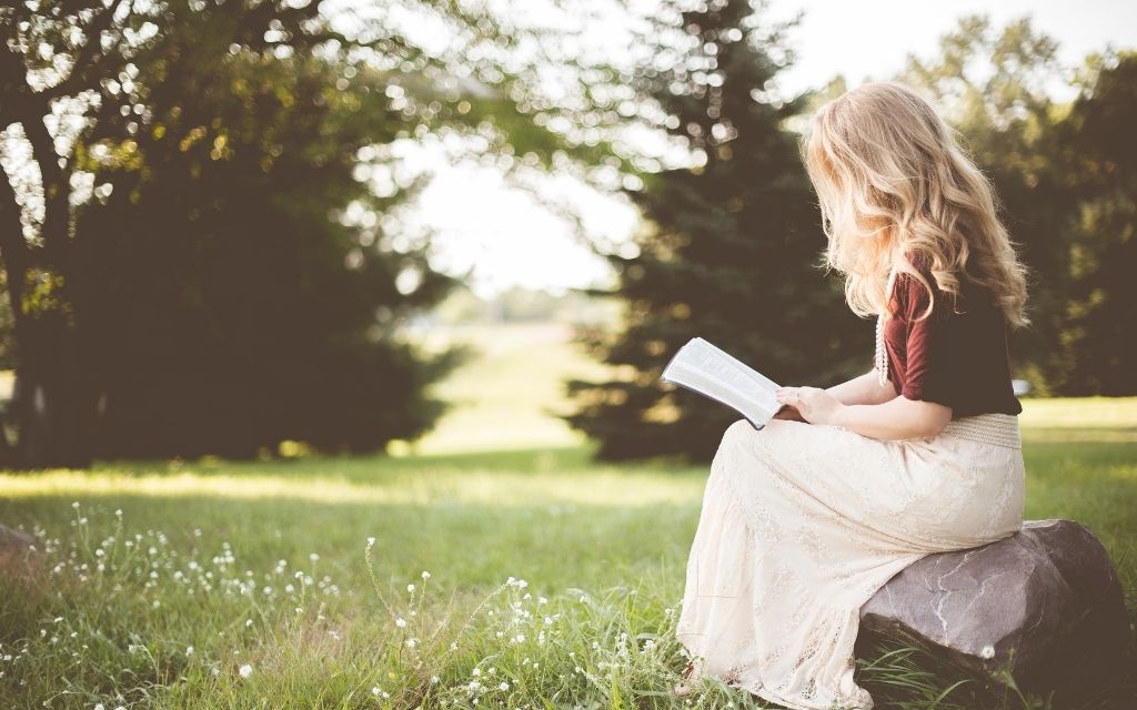 A woman reading the Bible in a garden; biblical meditation