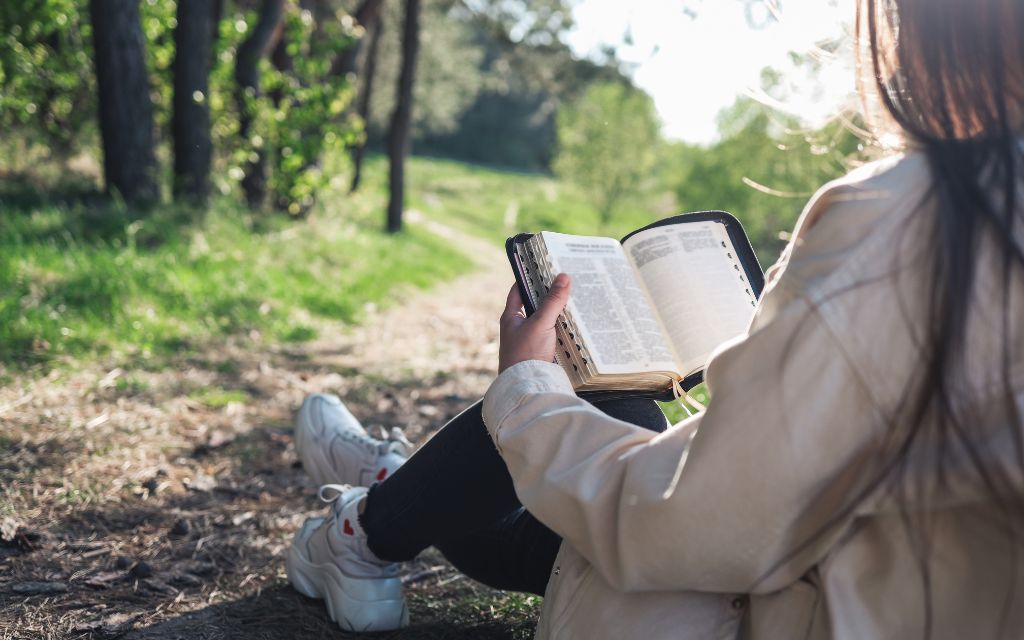 A woman reading the Bible in the woods