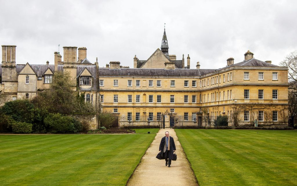 A man walking in front of an OXford college